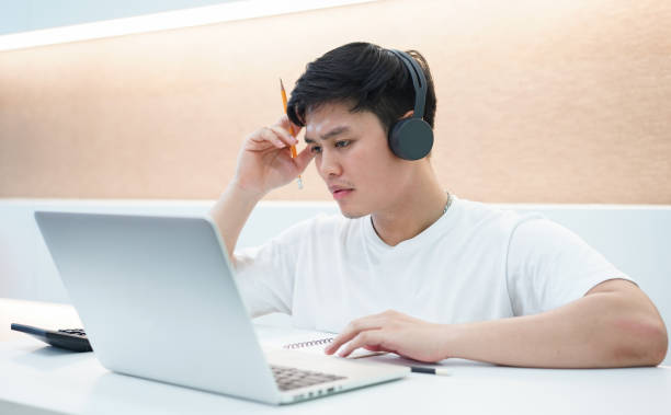 istock close up young asian student man wearing headset and looking at laptop display for learning online course from education website , concentrate on notebook for solve exam with serious mood at library concept 1128725102