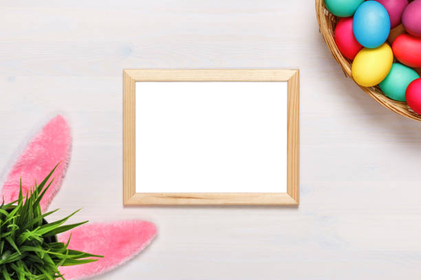 istock Frame, bunny ears, a flower pot with artificial green grass, colorful eggs in the basket. Easter concept. Copy space 1128725561