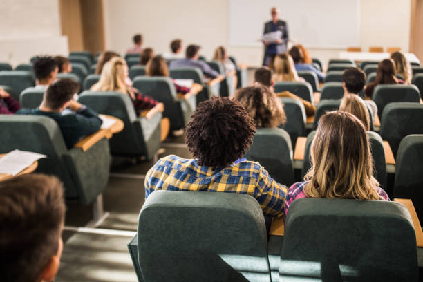 istock Back view of large group of students paying attention on a class at lecture hall. 1128725668