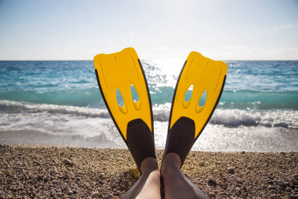 istock Womans legs with flippers on a beach 1128726707