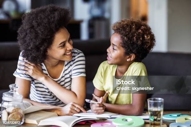 Happy African American Mother Assisting Her Daughter With Homework Stock Photo - Download Image Now