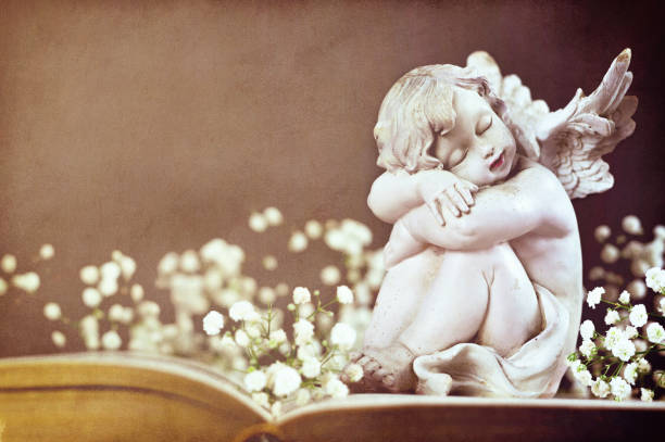 istock Cherub and white flowers on vintage book 1128733195
