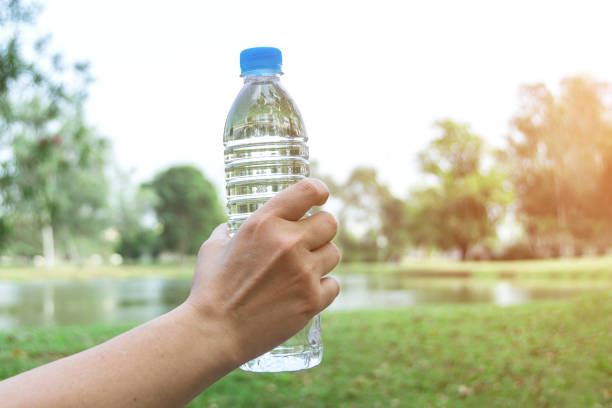 istock Hand holding drinking water bottle in nature background 1128733326