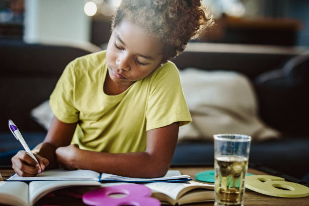 istock African American girl doing her homework at home. 1128733358