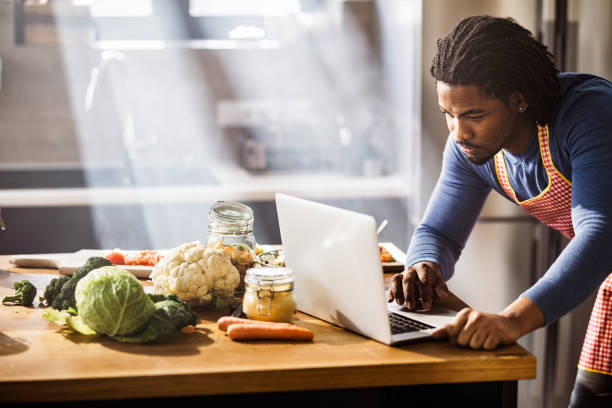 istock African American bachelor searching recipes over Internet in the kitchen. 1128733485
