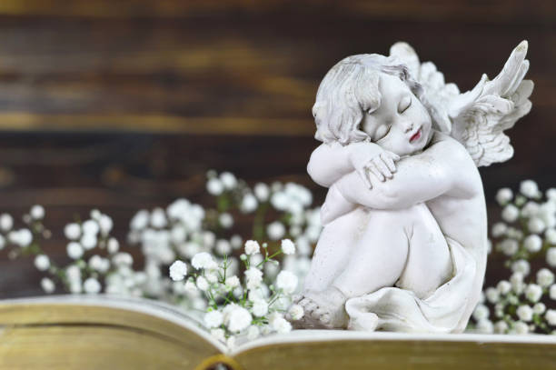 istock Angel and white flowers on vintage book 1128734511