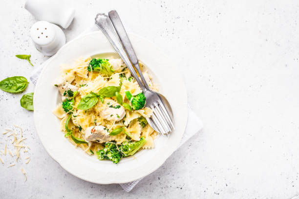 farfalle de pasta italiana con brócoli, pollo y queso en un plato blanco. - noodles pasta chicken breast color image fotografías e imágenes de stock