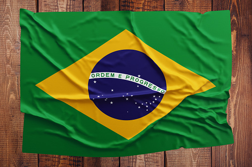 Flag of Brazil on a wooden table background. Wrinkled Brazilian flag top view.