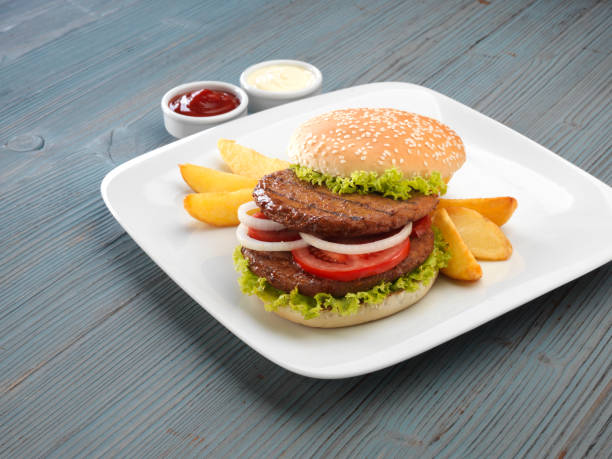 istock Hamburger with fried potatoes and sauces on wooden background. 1128737192