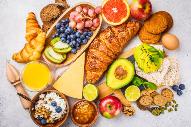 istock Healthy balanced breakfast on white background. Muesli, juice, croissants, cheese, biscuits and fruit, top view. 1128737451