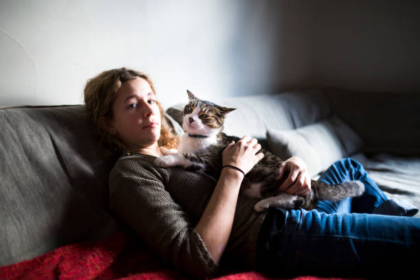 istock Beautiful young woman with her cat on a sofa 1128739961