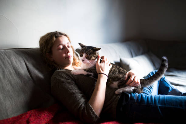 istock Beautiful young woman with her cat on a sofa 1128739985