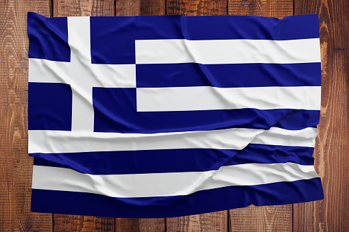 Flag of Greece on a wooden table background. Wrinkled Greek flag top view.