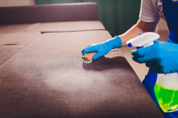 istock Cropped image. Cleaning concept. Male hand in light blue protective gloves cleaning sofa couch in the room. 1128740294