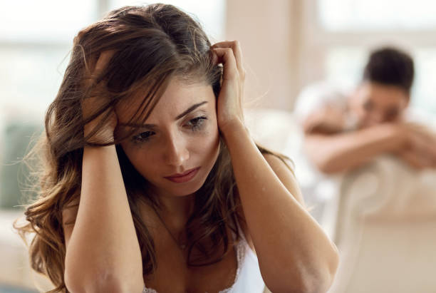 Does he even love anymore? Desperate young woman feeling disappointed after the conflict she had with her boyfriend. The man is sitting in the background. woman mascara smudged stock pictures, royalty-free photos & images