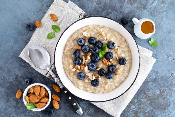 płatki owsiane ze świeżą surową jagodą, orzechami migdałowymi i miodem na śniadanie. zdrowe wegetariańskie jedzenie. widok z góry - oatmeal raisin porridge nut zdjęcia i obrazy z banku zdjęć