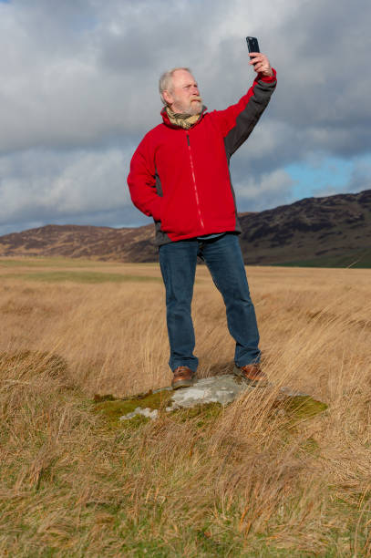 senior man using a mobile phone - fleece coat imagens e fotografias de stock