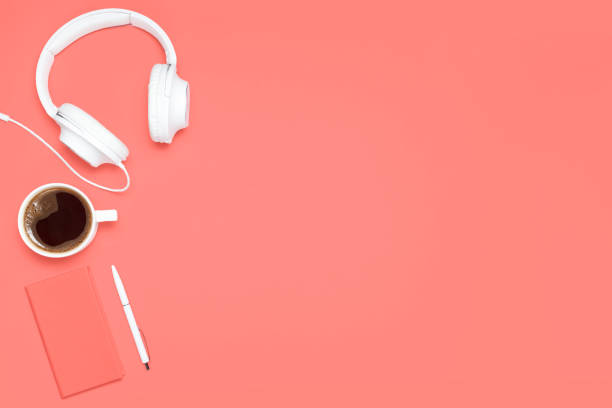 istock Trendy flat lay composition with coral colored diary, white pen, white cup of cofffee and white headphones on caral colored desk. Mockup with copy space for bloggers, designers, magazines etc 1128744821