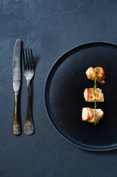 istock Grilled chicken breast in bacon. Dark background 1128745578