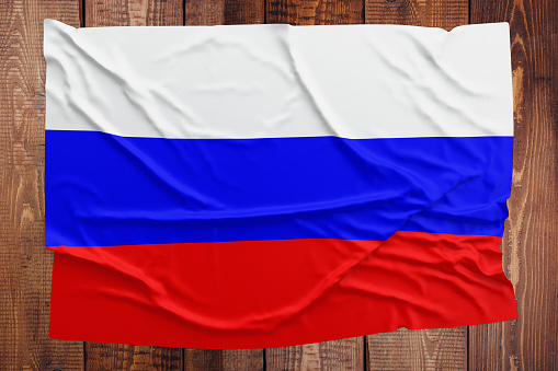 Flag of Russia on a wooden table background. Wrinkled Russian flag top view.