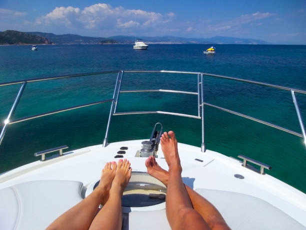 patas en blanco lujo yate con fondo de mar multicolor con 2 pequeños barcos en el horizonte. tema de vacaciones de relax de lujo - sport magazine day usa fotografías e imágenes de stock