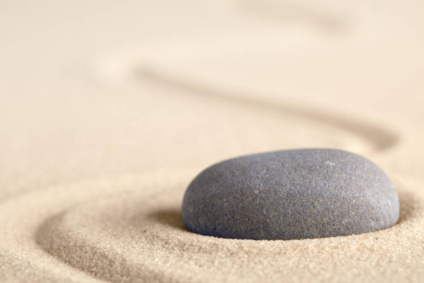 istock Zen meditation stone with raked line in sand 1128750122