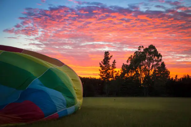 Tourists are treated to a beautiful sunrise as they wait for the hot air balloon to inflate in a rural field