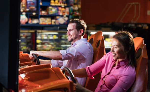 Two adults playing driving game in video arcade