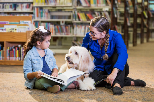 istock Hispanic girl reading in library with therapy dog 1128753083