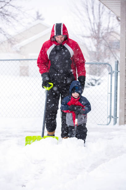 Cute little boy shoveling snow on the porch of his house after major snow storm in Toronto, Ontario, Canada on February 27, 2019. Outdoors winter activities. Winter fun for kids. Little kid shoveling snow. Winter outfit and shovel