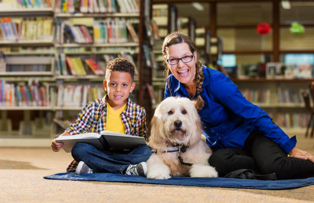istock Mixed race boy reading in library with therapy dog 1128755982