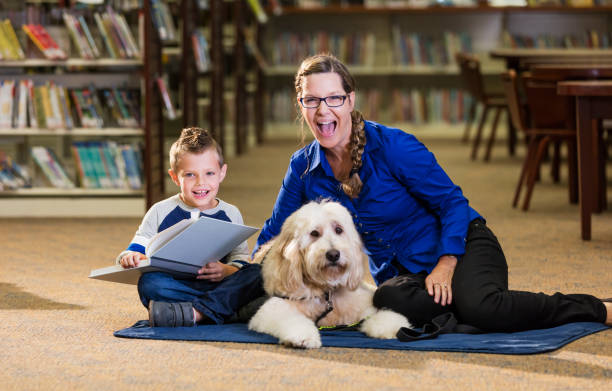 istock Mixed race boy reading in library with therapy dog 1128756066