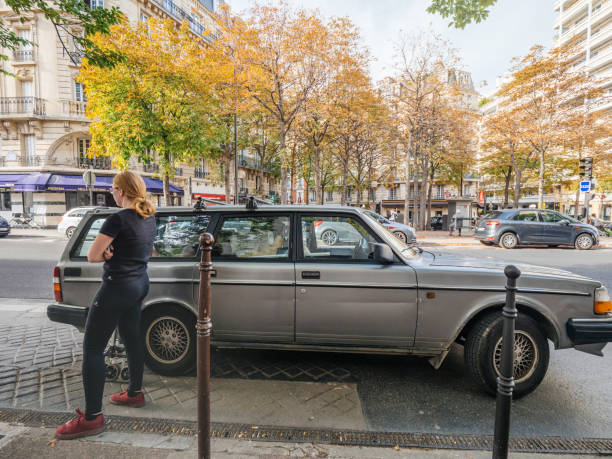 Woman wating near Volvo vintage 740 model Paris: Young French woman waiting near an old Volvo 740 Wagon car in Paris, on Rue d'Assas volvo 740 stock pictures, royalty-free photos & images