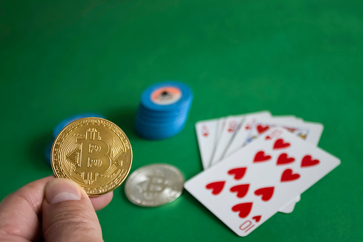 Cakovec, Croatia - February 19, 2018 : Two bitcoins laying down on green poker table and bunch of chips with cards in the background|gold|silver|blue|flush