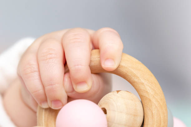 Close-up of a baby´s hand, playing with a wooden toy. Unfocused background stock photo