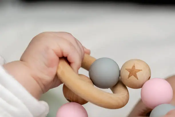 Close-up of a baby´s hand, playing with a wooden toy. Unfocused background