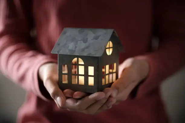 Miniature house model with illuminated light in the hand