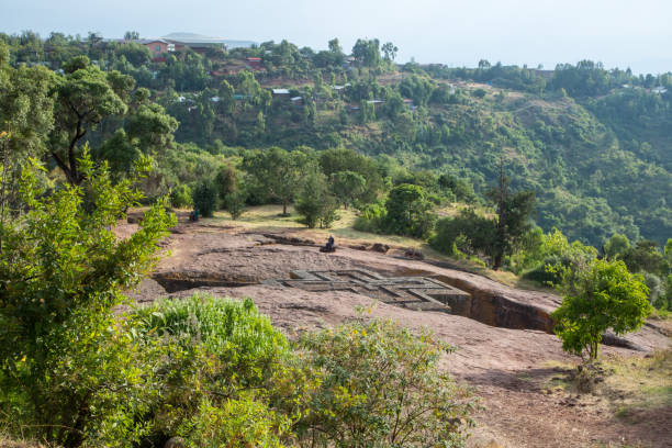 Ethiopia: Church of St. George in Lalibela Visitors marvel at the iconic Church of St. George (Biete Ghirogis) in Lalibela. Built in the late 12th or early 13th century AD, it is one of eleven rock-hewn monolithic churches that are now a UNESCO World Heritage Site. the church of saint george lalibela ethiopia stock pictures, royalty-free photos & images