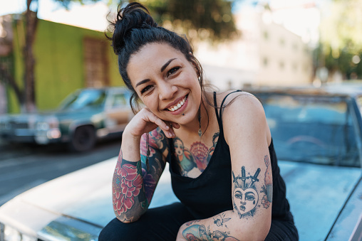 Retrato de hermosa Latina /Mexican milenaria mujer con tatuajes sentado en la capilla del coche photo