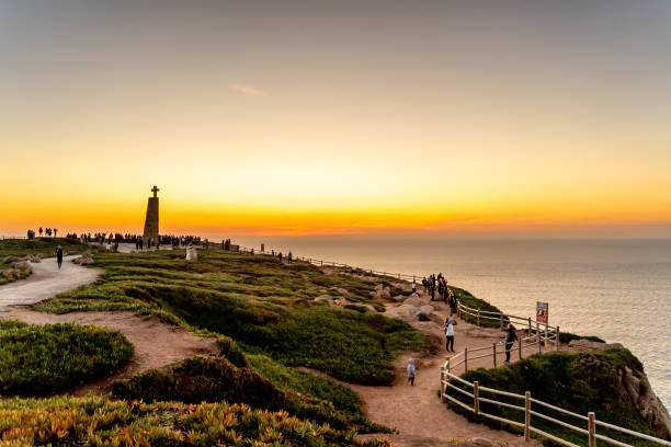 menschen am rande europas bei sonnenuntergang, kap roca - cliff at the edge of grass sea stock-fotos und bilder