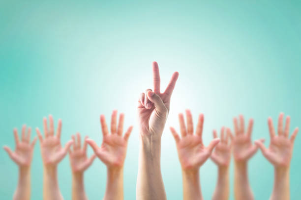 istock Leader's two fingers victory sign among blur hands crowd group for World participation, leadership, volunteer concept 1128780797