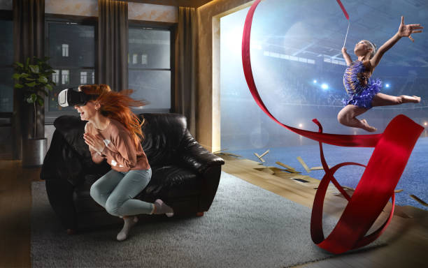 Beautiful woman at home on a black sofa with VR headset makes difficult gymnastic trick in virtual reality