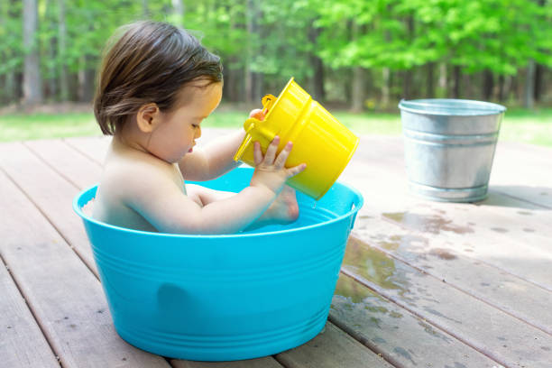 Toddler boy playing in a little bath tub outside