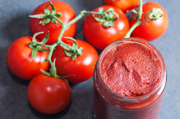 istock Tomato Paste in wooden spoon or jar and ripe fresh grape tomatoes on wooden background. Cherry tomatoes. Tomato sauce ketchup food concept 1128785251