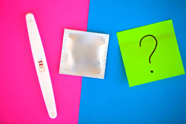 test de grossesse. le résultat est positif avec deux bandes et préservatif avec contraceptif sur fond coloré, pilule contraceptive, safe sex, concept de soins de santé - contraceptive sex education birth control pill condom photos et images de collection