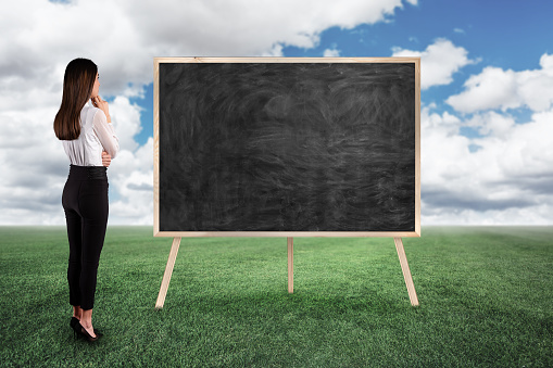 Businesswoman looking and thinking blackboard