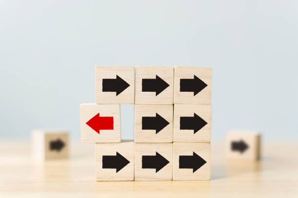 istock Wooden block with red arrow facing the opposite direction black arrows, Unique, think different, individual and standing out from the crowd concept 1128789457