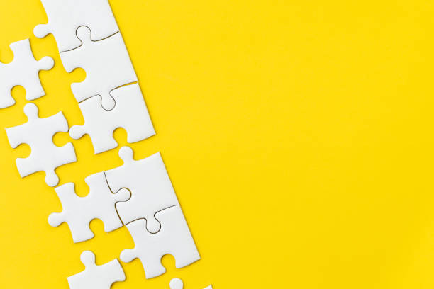 istock White jigsaw puzzle on vivid yellow background with copy space using for thinking strategy for business solution, teamwork, connection or idea for success 1128795622