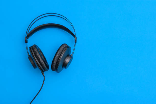 istock Black headphones with coiled cord on light blue background. 1128811014