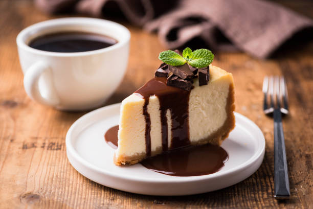 Cheesecake with chocolate sauce and cup of black coffee Cheesecake with chocolate sauce and cup of black coffee on a wooden table. Tasty snack or coffee time with slice of cake dessert stock pictures, royalty-free photos & images